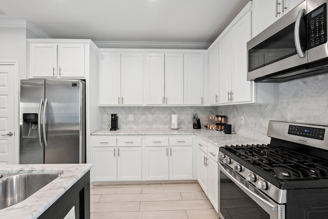 kitchen featuring tasteful backsplash, stainless steel appliances, white cabinets, and light stone countertops