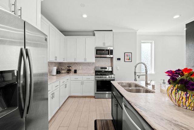 kitchen with stainless steel appliances, white cabinetry, sink, backsplash, and light stone counters