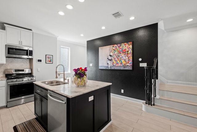 kitchen with appliances with stainless steel finishes, backsplash, sink, white cabinetry, and crown molding