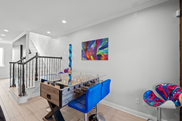 recreation room featuring ornamental molding and light hardwood / wood-style floors