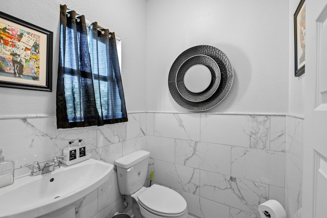 bathroom with tile walls, toilet, and sink