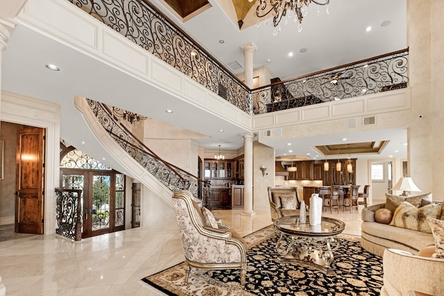 living room featuring ornate columns, a high ceiling, and a notable chandelier