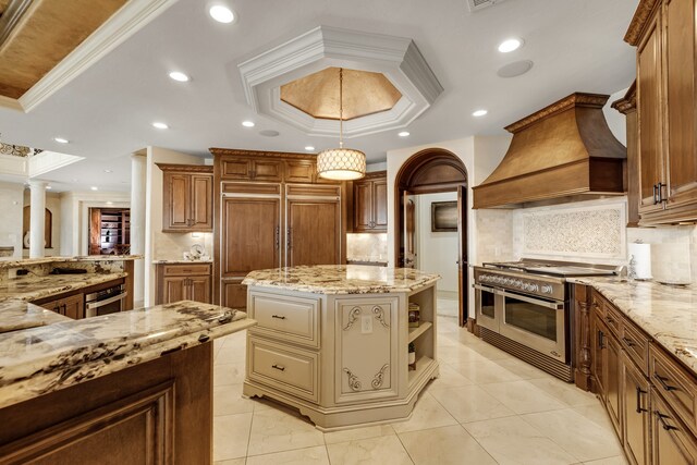 kitchen featuring backsplash, ornamental molding, a tray ceiling, and a center island