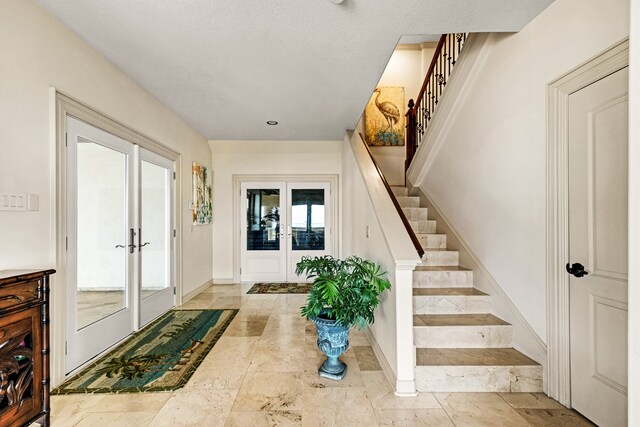 tiled foyer with plenty of natural light, a textured ceiling, and french doors