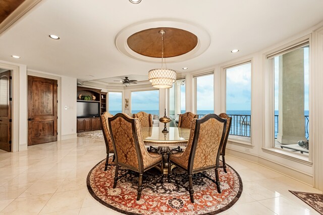 dining space with a raised ceiling, a water view, ceiling fan, and light tile floors