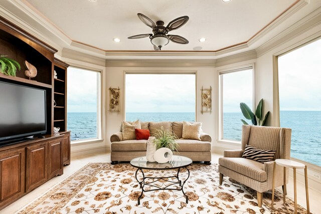 living room featuring a water view, ornamental molding, ceiling fan, and a wealth of natural light