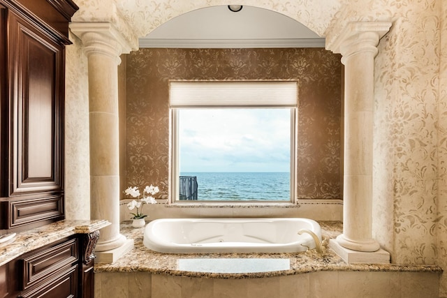 bathroom with ornate columns, a water view, and tiled tub