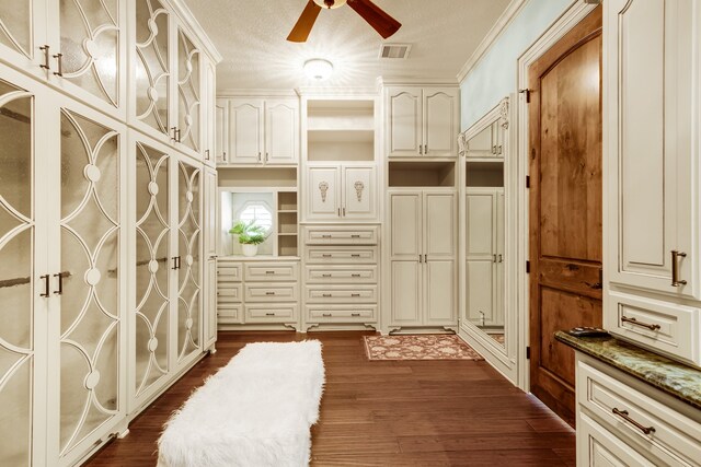 interior space featuring ceiling fan, a textured ceiling, dark wood-type flooring, and ornamental molding