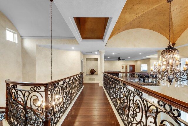 hall with ornate columns, dark wood-type flooring, a chandelier, and a healthy amount of sunlight