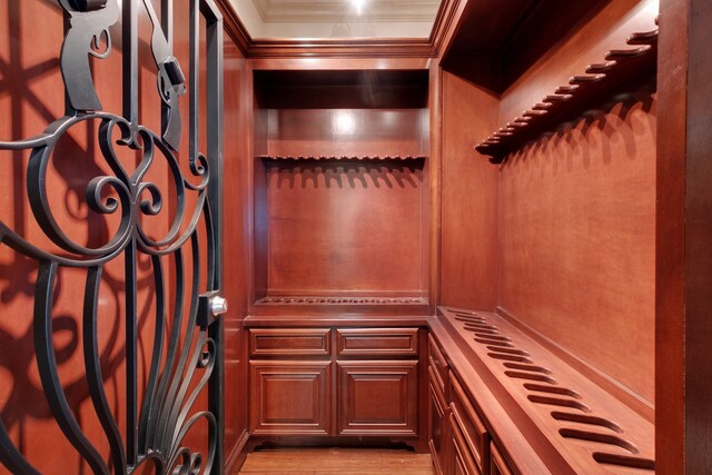 wine cellar featuring light hardwood / wood-style floors and ornamental molding