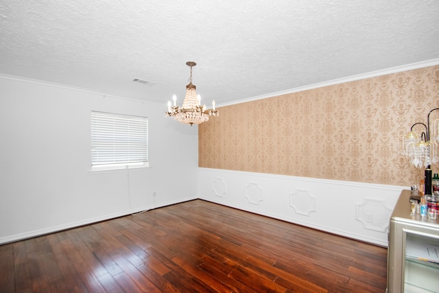 spare room featuring dark hardwood / wood-style flooring, ornamental molding, and a chandelier