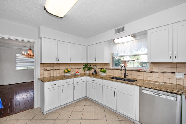 kitchen featuring stainless steel dishwasher, light tile flooring, sink, white cabinets, and an inviting chandelier