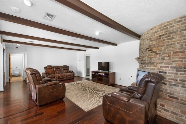 living room featuring dark wood-type flooring, a textured ceiling, and beam ceiling