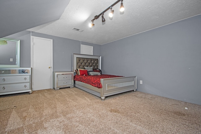 bedroom featuring a textured ceiling, track lighting, and light carpet