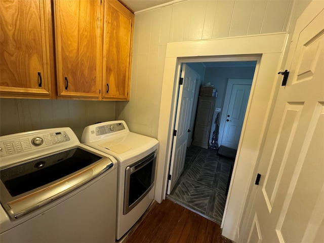 clothes washing area with washing machine and clothes dryer, cabinets, and dark wood-type flooring