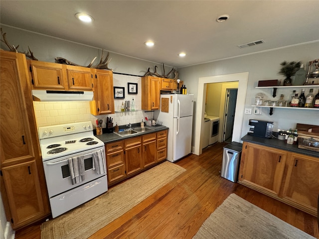 kitchen with sink, white appliances, dark hardwood / wood-style floors, and tasteful backsplash