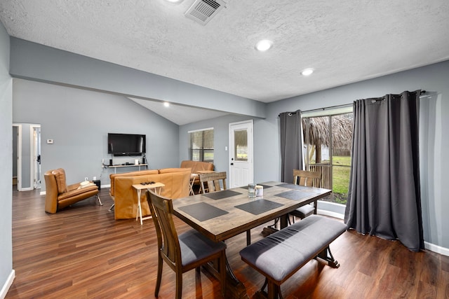 dining area featuring a textured ceiling, lofted ceiling, and dark hardwood / wood-style floors