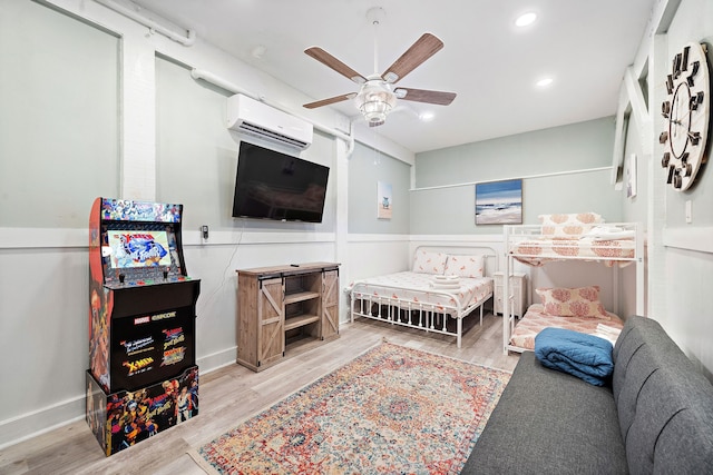 bedroom with an AC wall unit, ceiling fan, and light hardwood / wood-style flooring