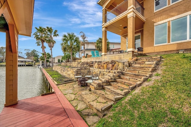 view of yard featuring a dock, a balcony, a patio, and a water view