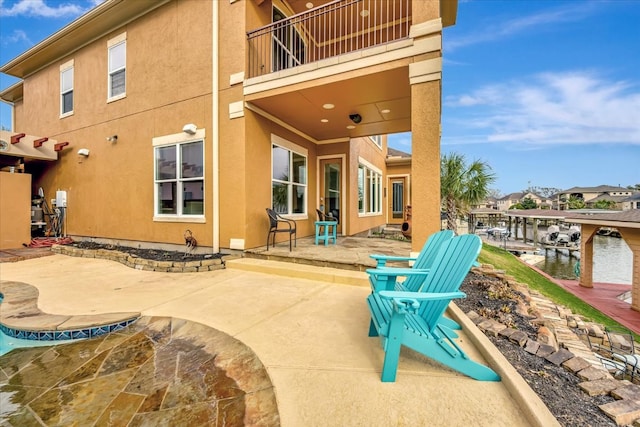 rear view of property with a water view, a balcony, and a patio