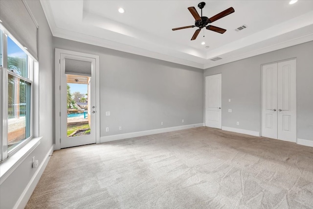 carpeted spare room with crown molding, a tray ceiling, and ceiling fan