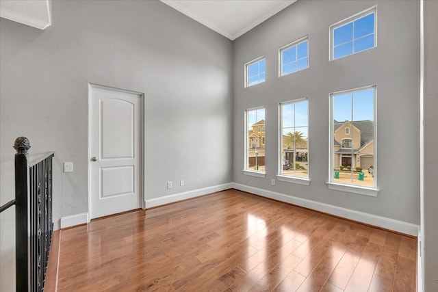 unfurnished living room featuring crown molding, a towering ceiling, and hardwood / wood-style flooring