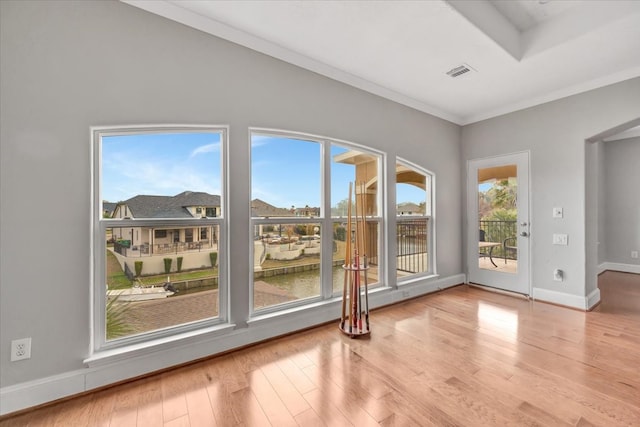 doorway with crown molding, light hardwood / wood-style floors, and a water view