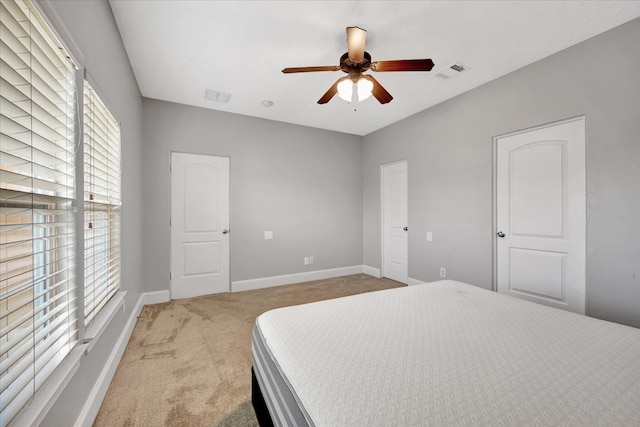 bedroom with multiple windows, ceiling fan, and light colored carpet