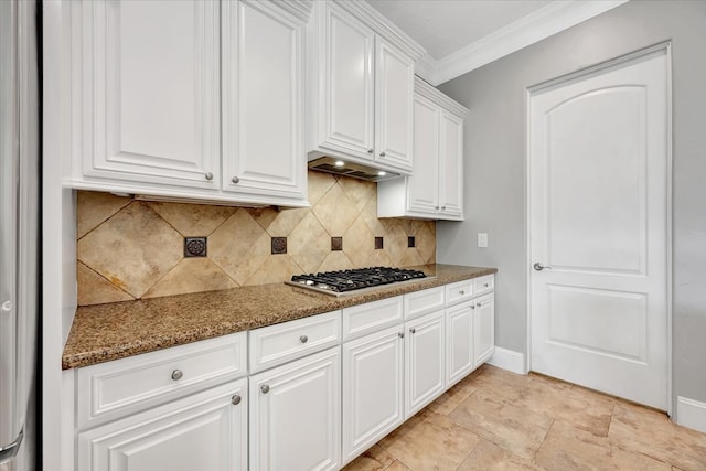 kitchen featuring dark stone counters, white cabinetry, stainless steel gas cooktop, decorative backsplash, and crown molding