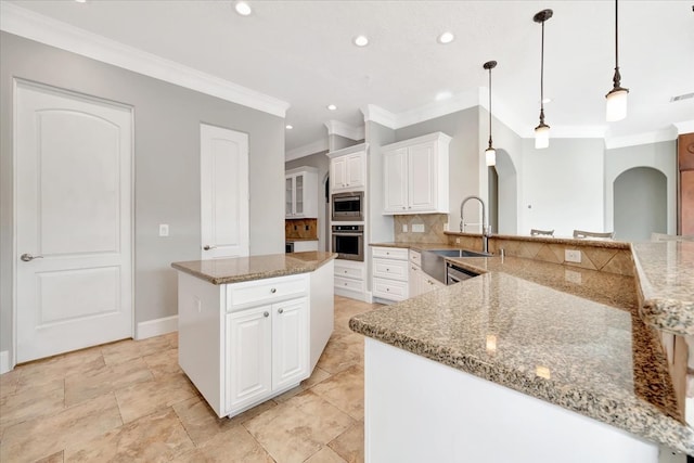 kitchen featuring a large island, light stone countertops, sink, and white cabinetry