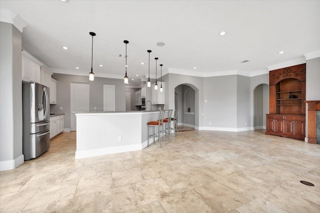 kitchen with ornamental molding, white cabinets, hanging light fixtures, and stainless steel fridge with ice dispenser