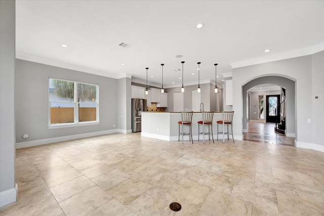 kitchen with stainless steel fridge, white cabinetry, pendant lighting, and ornamental molding