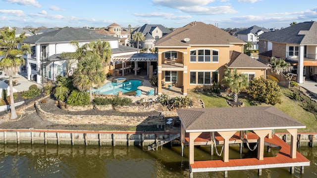 rear view of house with a pool with hot tub, a water view, and a patio