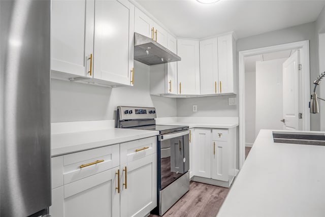 kitchen with stainless steel appliances, light hardwood / wood-style flooring, wall chimney exhaust hood, and white cabinetry