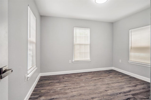 empty room with dark hardwood / wood-style flooring and a wealth of natural light