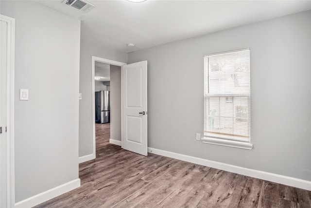 spare room with wood-type flooring and a healthy amount of sunlight