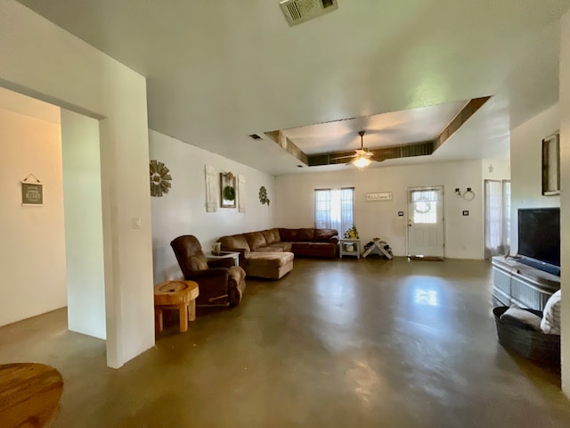 living room featuring a raised ceiling and ceiling fan