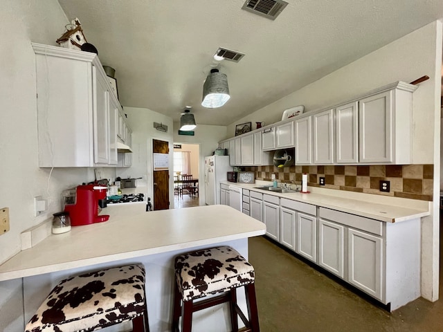 kitchen with a breakfast bar area, kitchen peninsula, custom range hood, and white cabinets