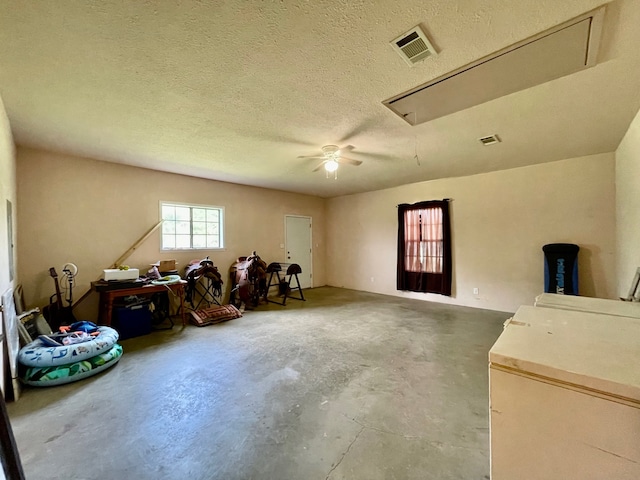 miscellaneous room with ceiling fan, a textured ceiling, and concrete flooring