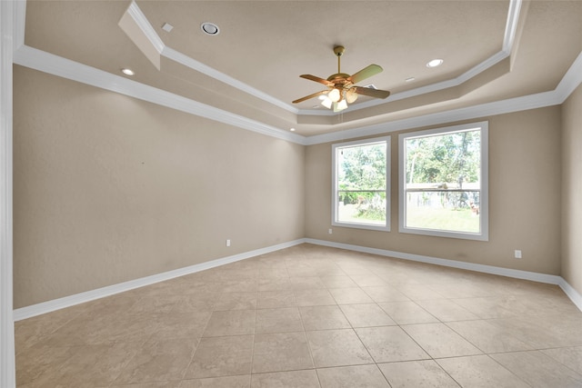 tiled empty room with crown molding and a tray ceiling