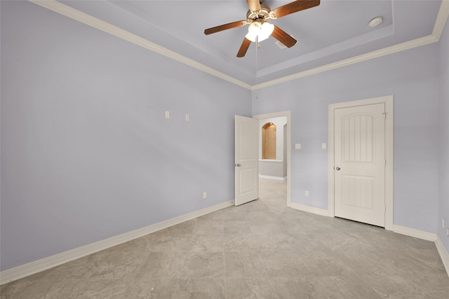 empty room with crown molding, a tray ceiling, and ceiling fan