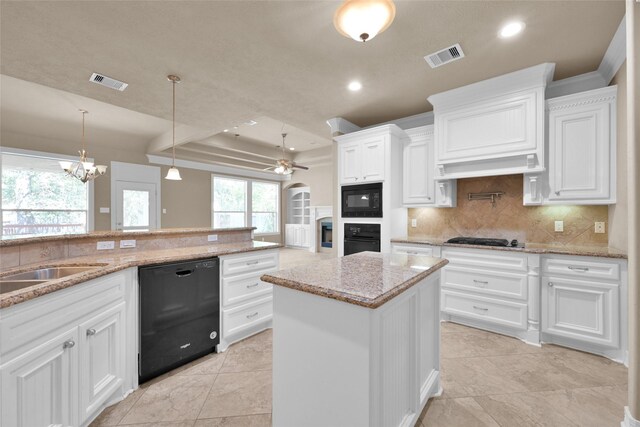 kitchen with black appliances, a kitchen island, ceiling fan with notable chandelier, white cabinetry, and decorative backsplash