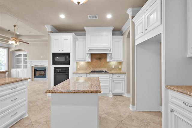 kitchen with white cabinets, light stone counters, black appliances, and ceiling fan