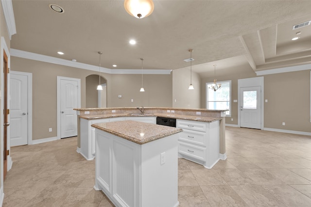 kitchen featuring white cabinetry, light stone counters, an island with sink, and hanging light fixtures