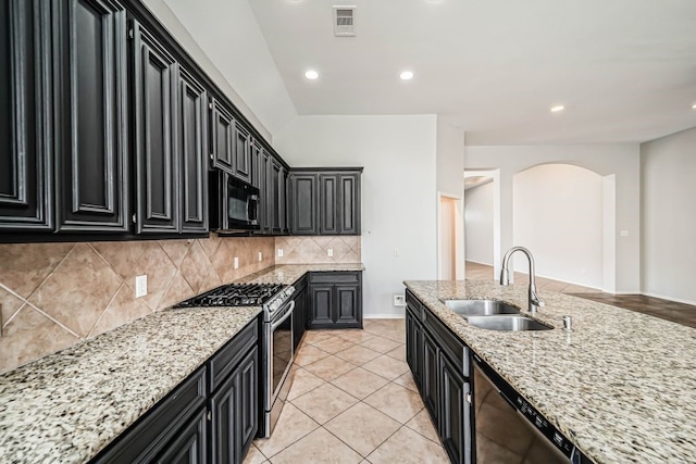 kitchen featuring backsplash, light tile flooring, sink, stainless steel appliances, and light stone counters