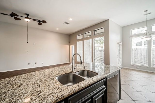 kitchen featuring light tile floors, light stone counters, dishwasher, and sink