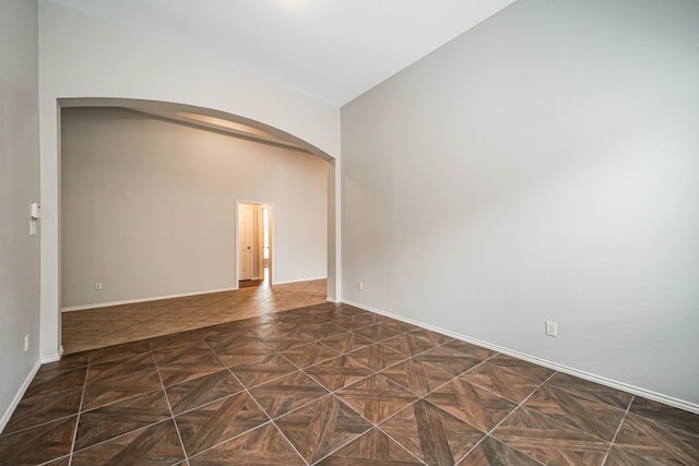 unfurnished room featuring lofted ceiling and dark parquet floors