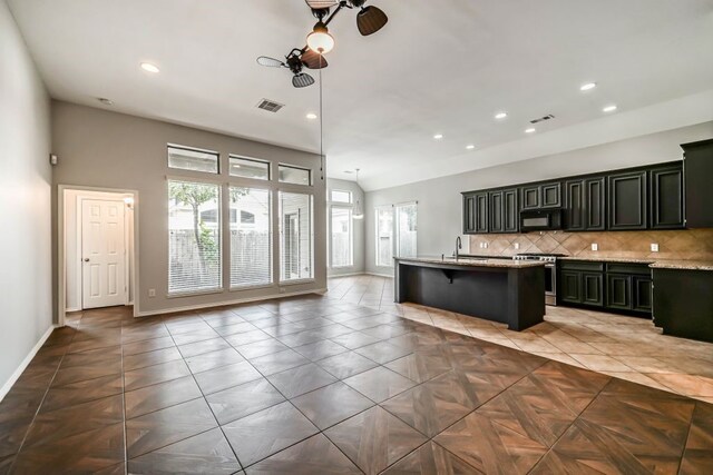 kitchen featuring dark tile floors, pendant lighting, tasteful backsplash, a kitchen bar, and stainless steel stove