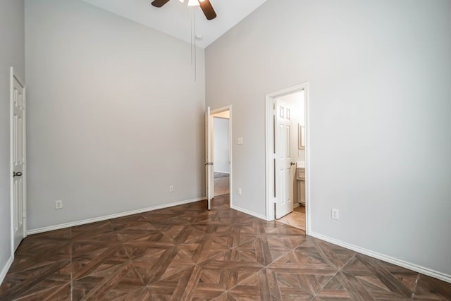 unfurnished bedroom with dark parquet floors, high vaulted ceiling, ceiling fan, and connected bathroom