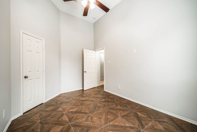 unfurnished room with high vaulted ceiling, dark parquet floors, and ceiling fan